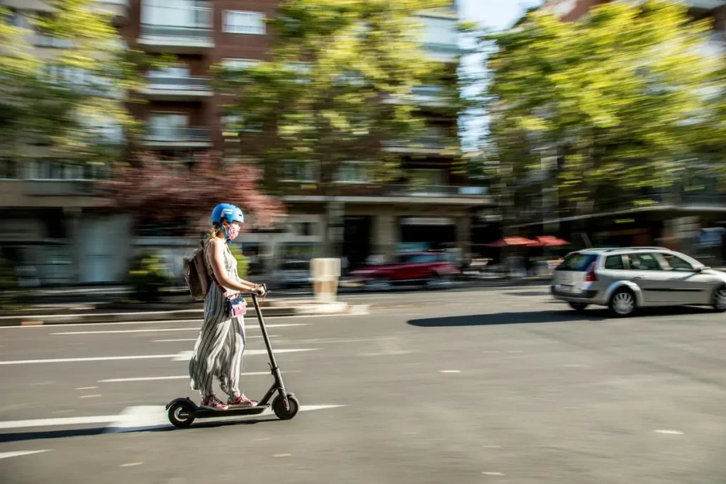 Frau fährt mit einem E-Scooter im Straßenverkehr.