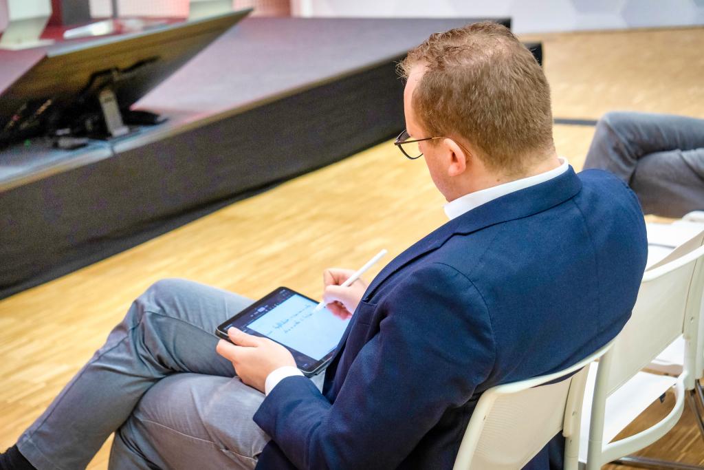 Mann schreibt etwas auf ein Tablet